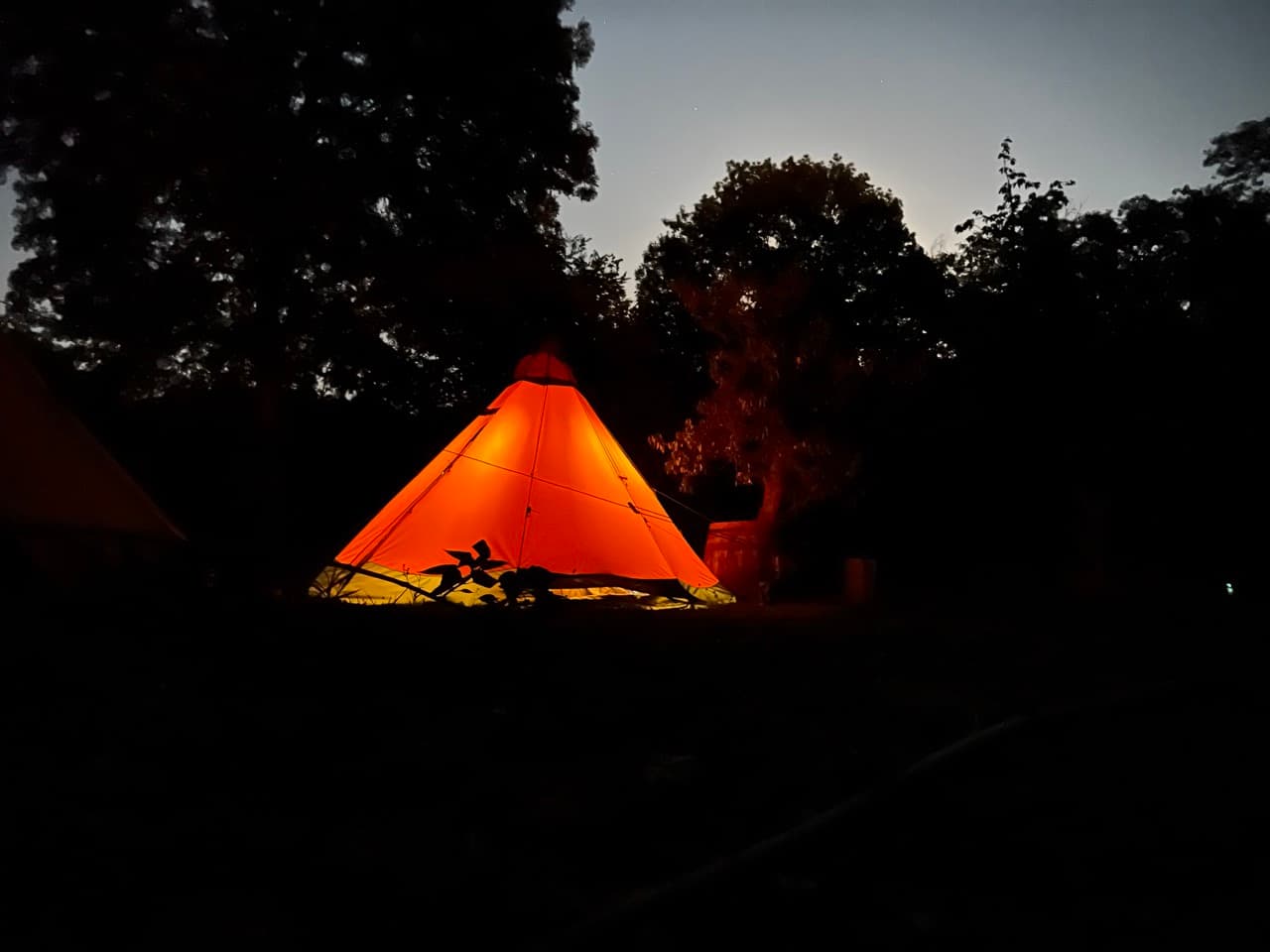 Illuminated tipi at dusk with glowing warm light