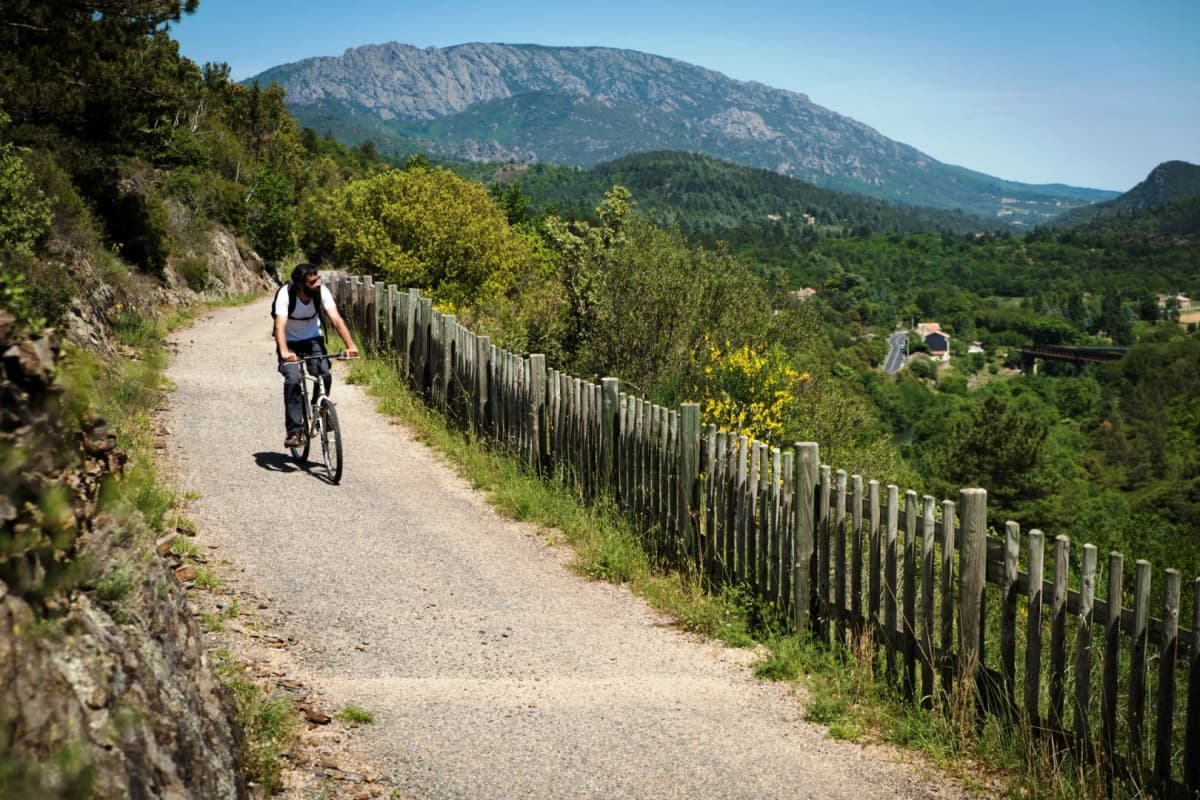 Scenic Passa Païs greenway with wooden fence and mountain backdrop