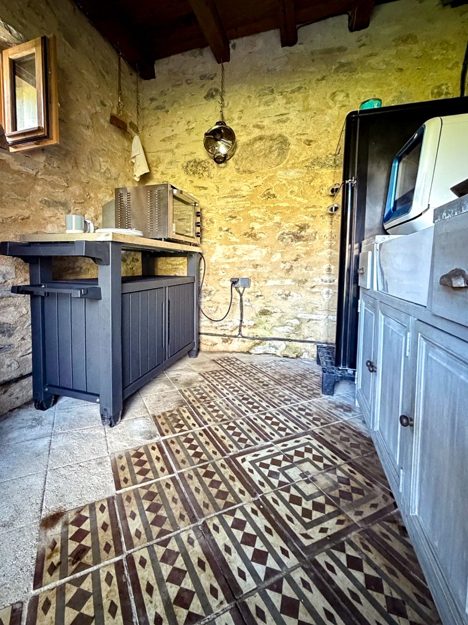 Kitchenette Pigeonnier interior with stone walls, sink, and appliances