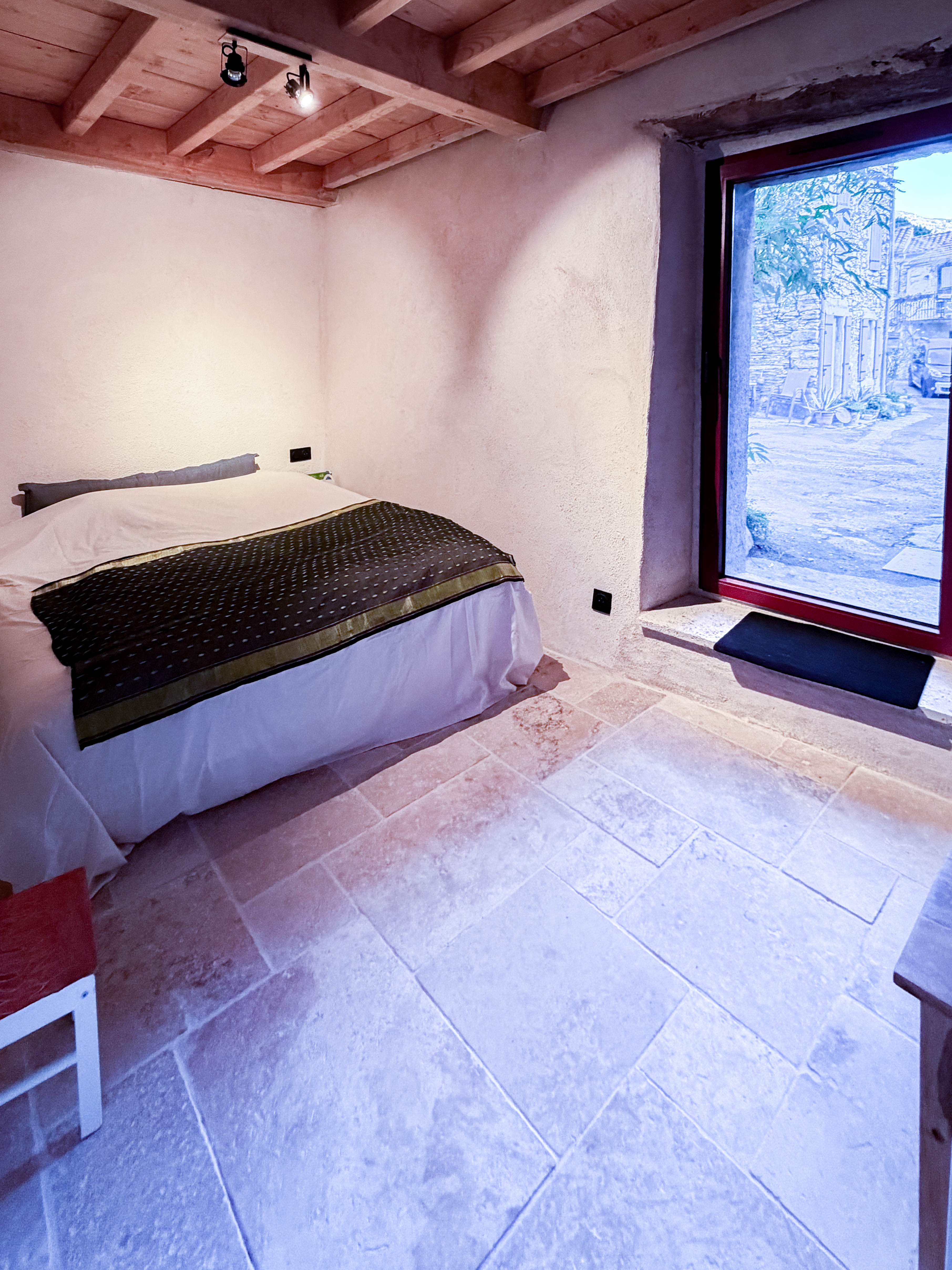 Bedroom with red-framed door opening to courtyard