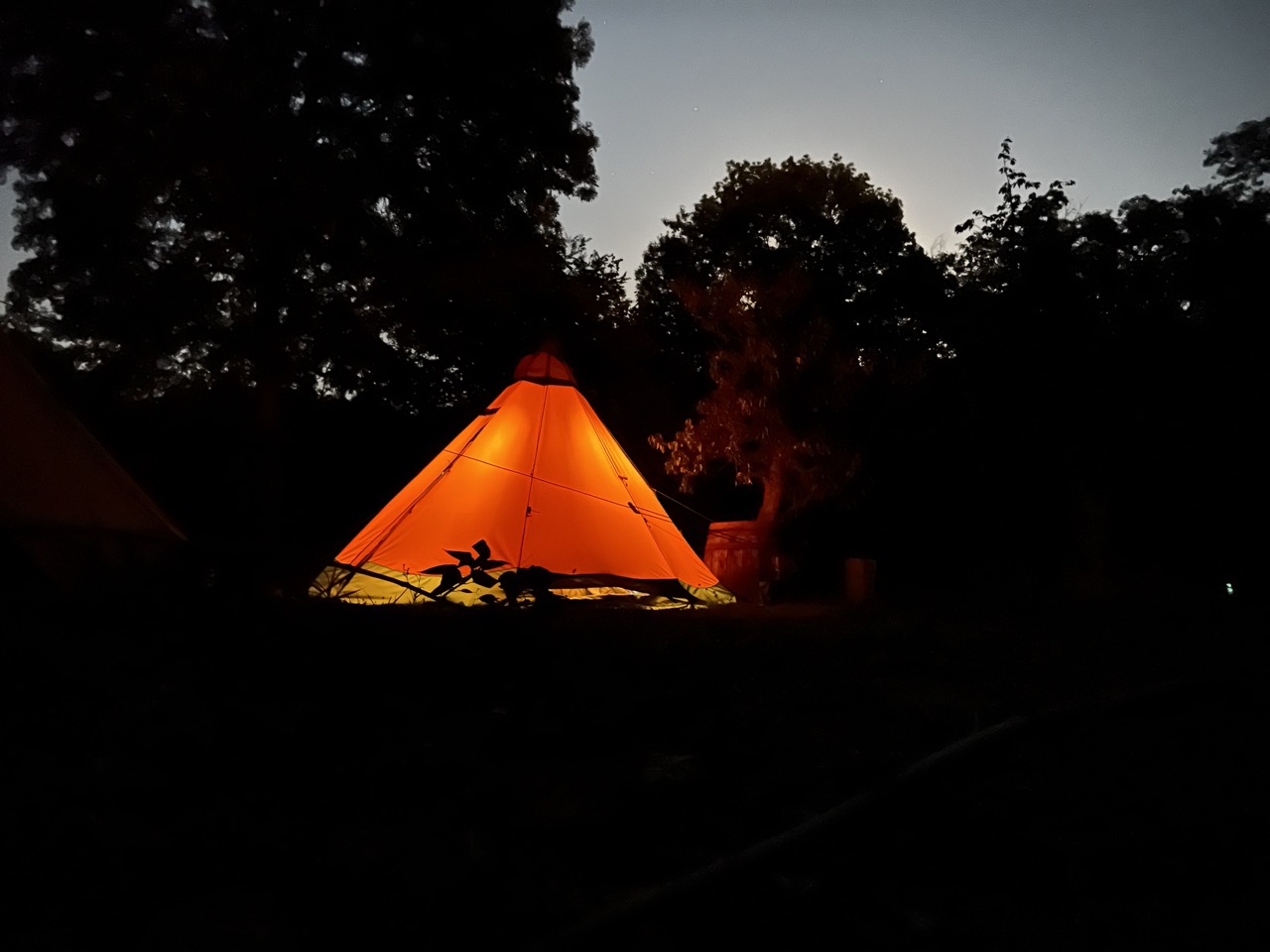 Illuminated tipi at dusk with glowing warm light