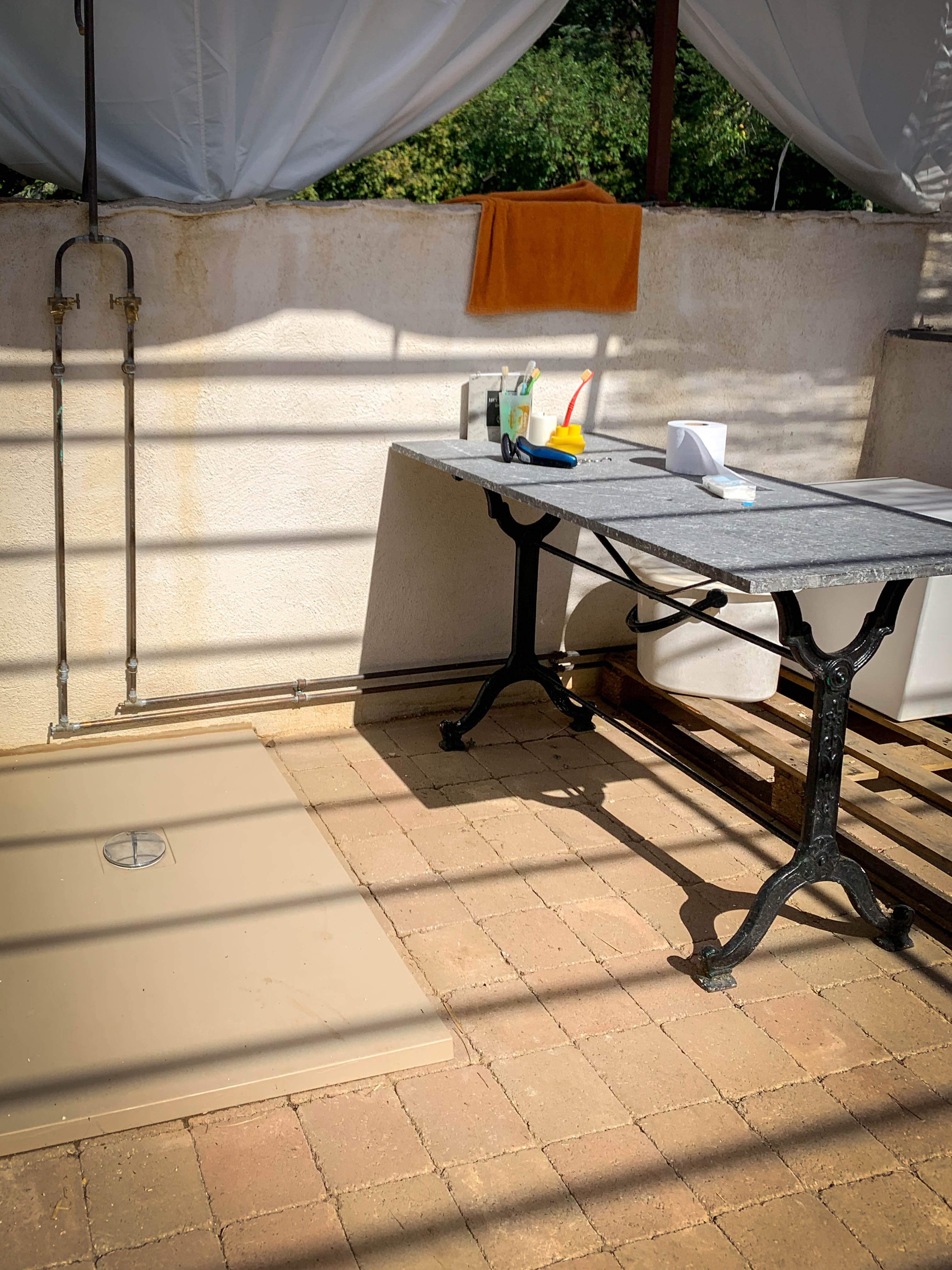 Outdoor shower area with vintage marble table and brass fixtures