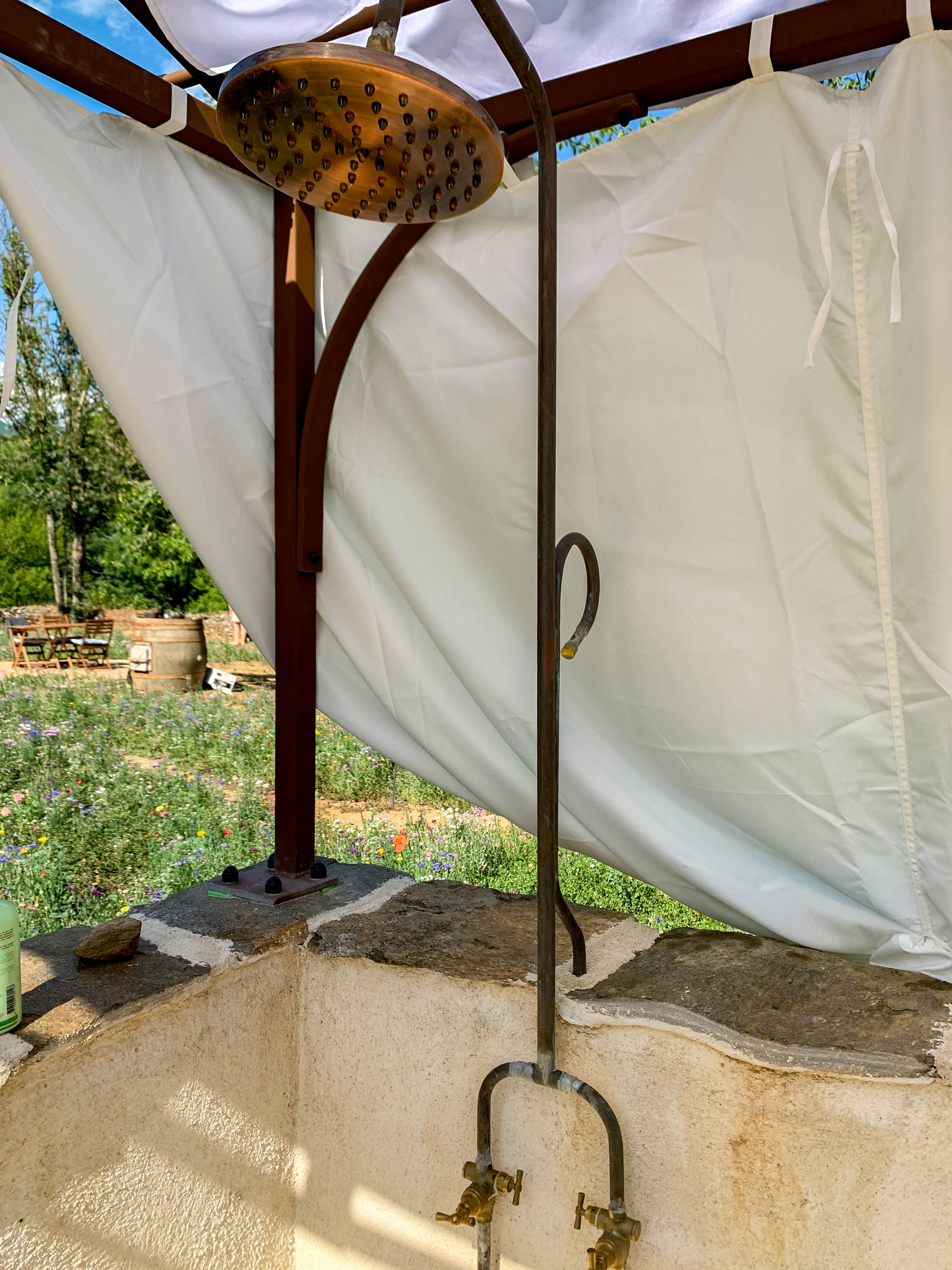 Brass rainfall shower head with wildflower garden view